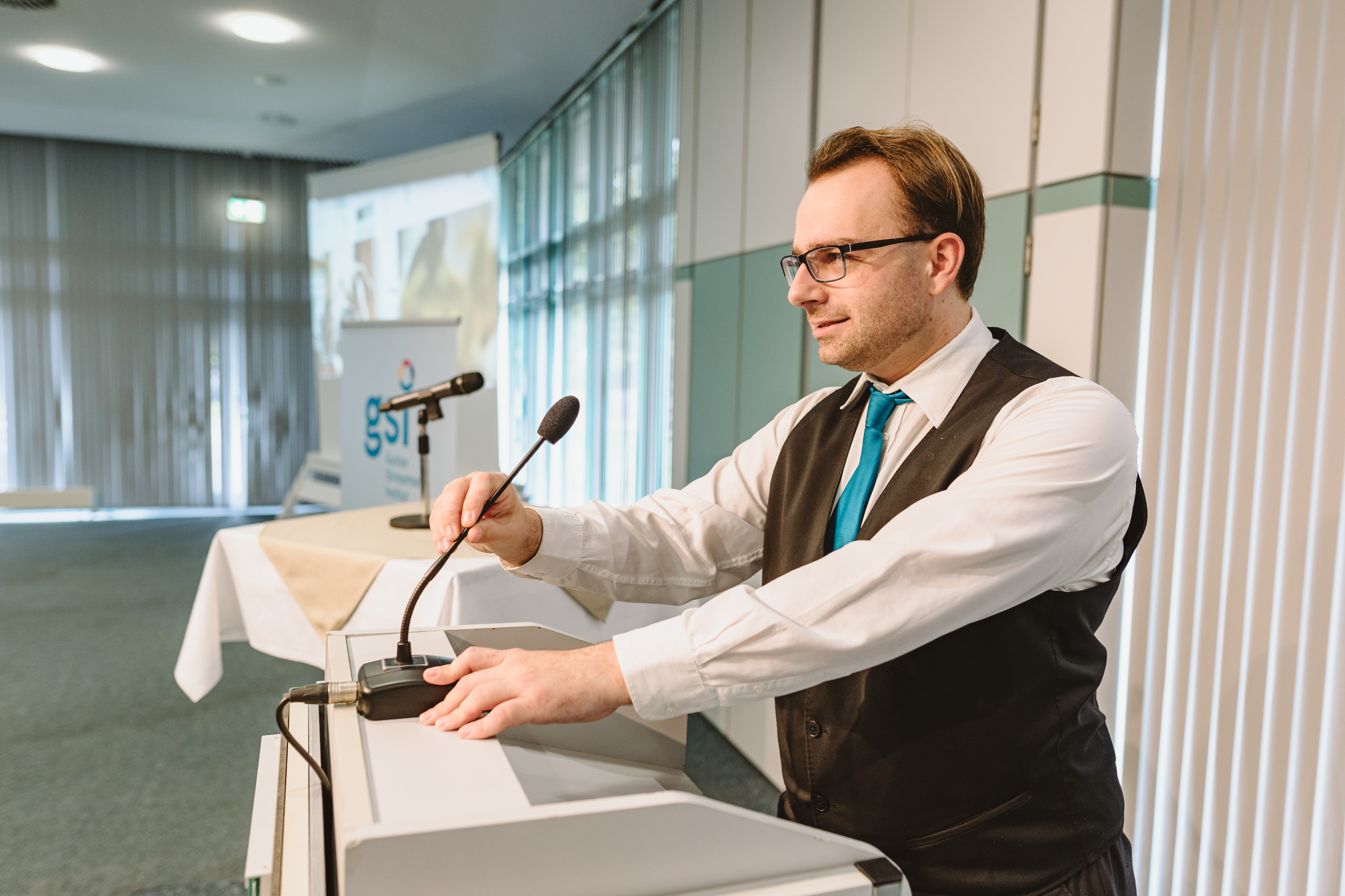 Ein Techniker sorgt für den reibungslosen Ablauf einer Veranstaltung und nimmt Einstellungen an einem Mikrofon vor..